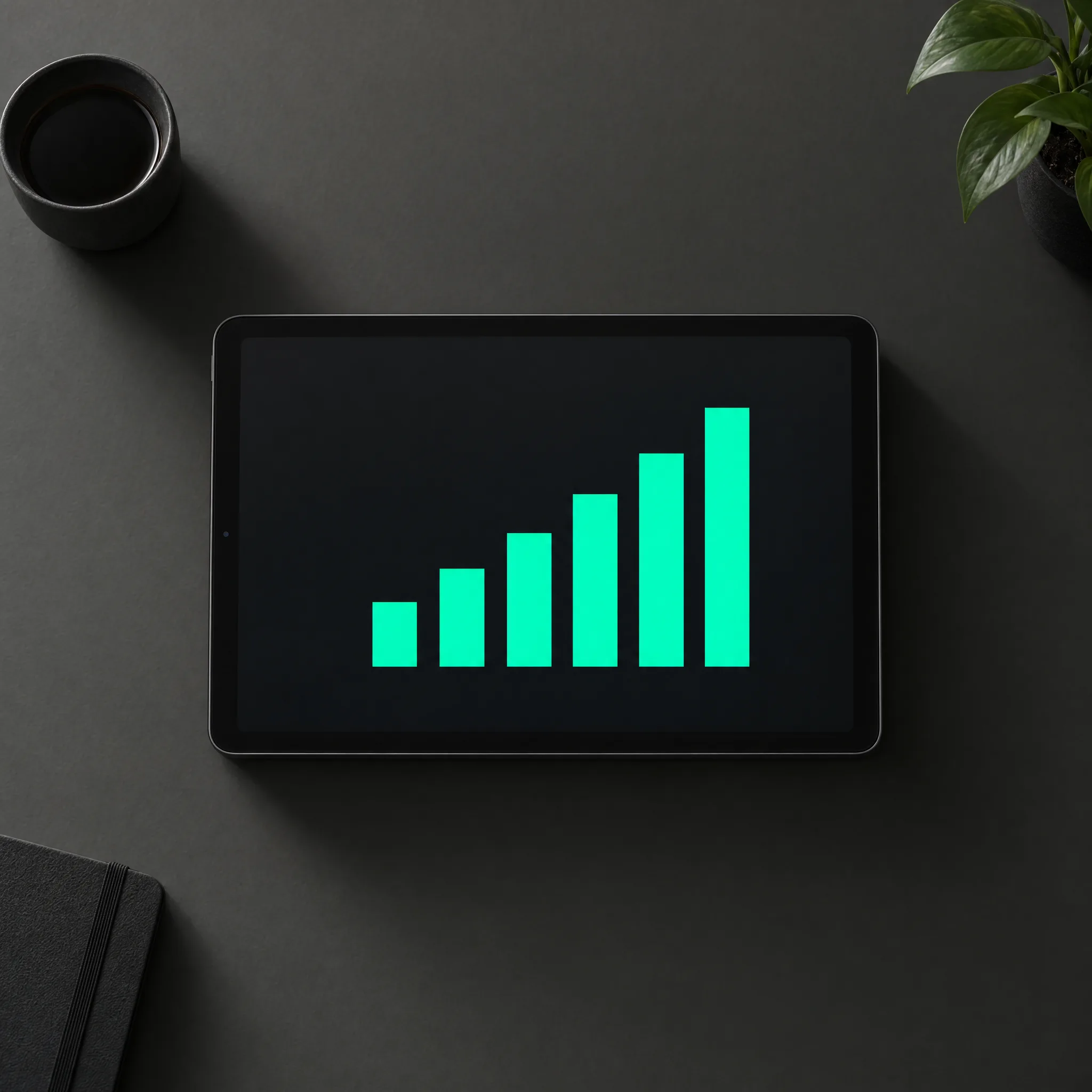A tablet showing a rising bar chart in teal on a dark desk